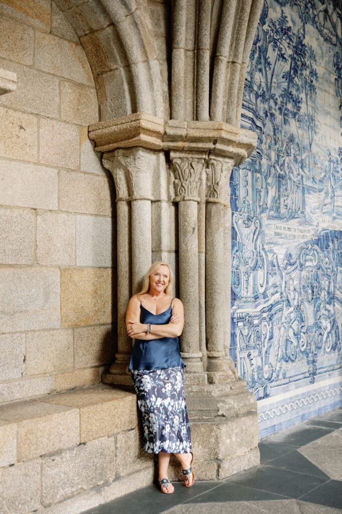 Leaning against a stone column at Porto Cathedral with blue azulejo tiles