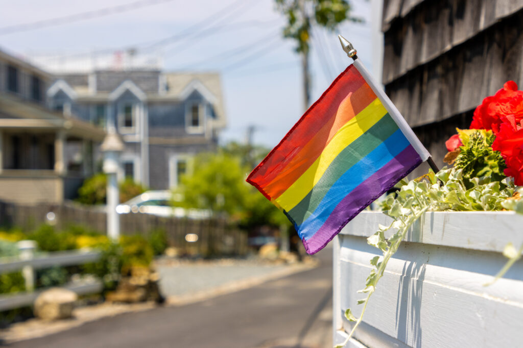 A gay pride flag waves from a window box in a residential district.